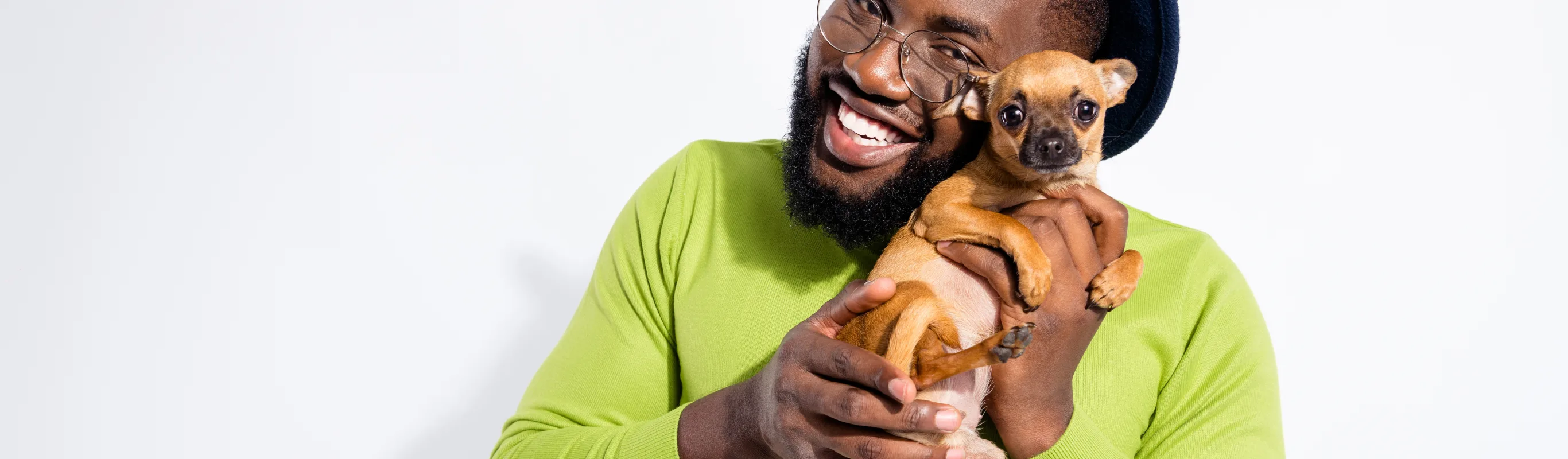 Man wearing green shirt and hat holding a puppy to his face